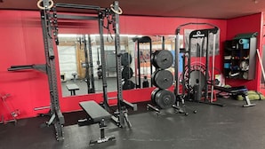 A gym with weightlifting equipment, a bench, and a mirror.