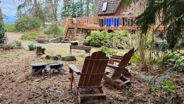 A rustic cabin with a deck, outdoor seating, and a garden area.