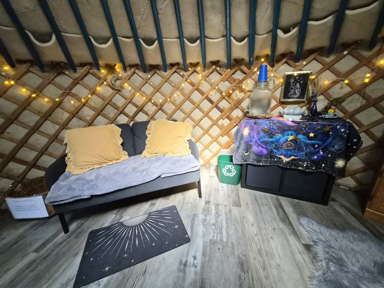 A cozy room with a bed, a small table with a decorative item, and a wall with a lattice pattern.