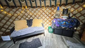 A cozy room with a bed, a small table with a decorative item, and a wall with a lattice pattern.