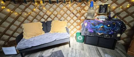 A cozy room with a bed, a small table with a decorative item, and a wall with a lattice pattern.