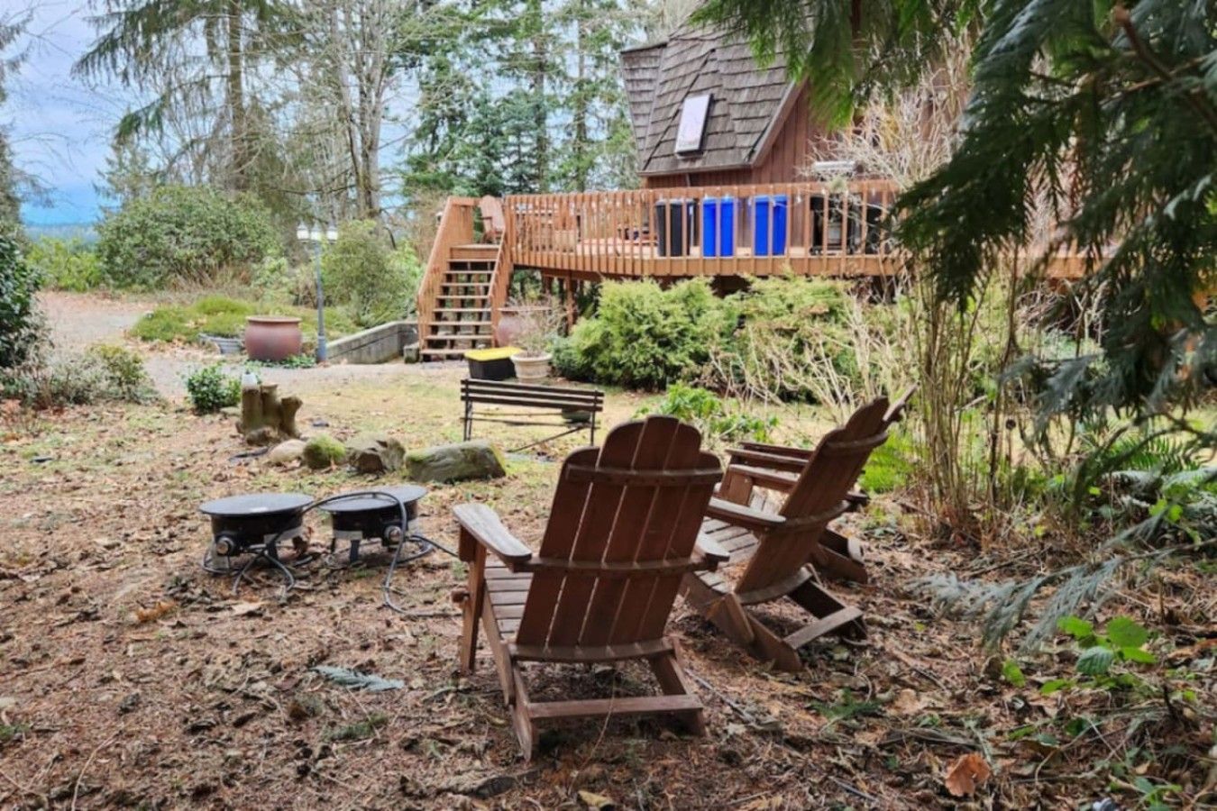 Une terrasse en bois avec des fauteuils Adirondack, un foyer et une structure en bois dotée d’un balcon.