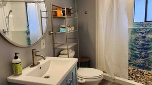 Un baño con lavamanos, inodoro y zona de ducha.