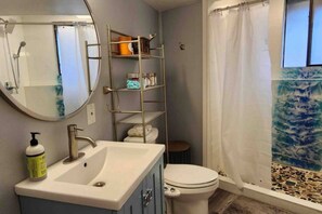 Un baño con lavamanos, inodoro y zona de ducha.