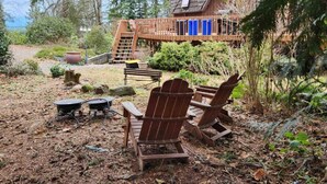 A rustic cabin with a wooden deck, outdoor seating, and a scenic forest backdrop.