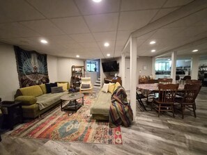 A living room with a sofa, armchair, coffee table, and a dining area with chairs and a table.