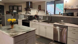 A modern kitchen with white cabinets, stainless steel appliances, and a large window providing natural light.