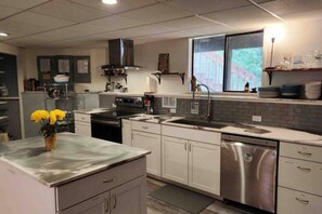 A modern kitchen with white cabinets, stainless steel appliances, and a window providing natural light.