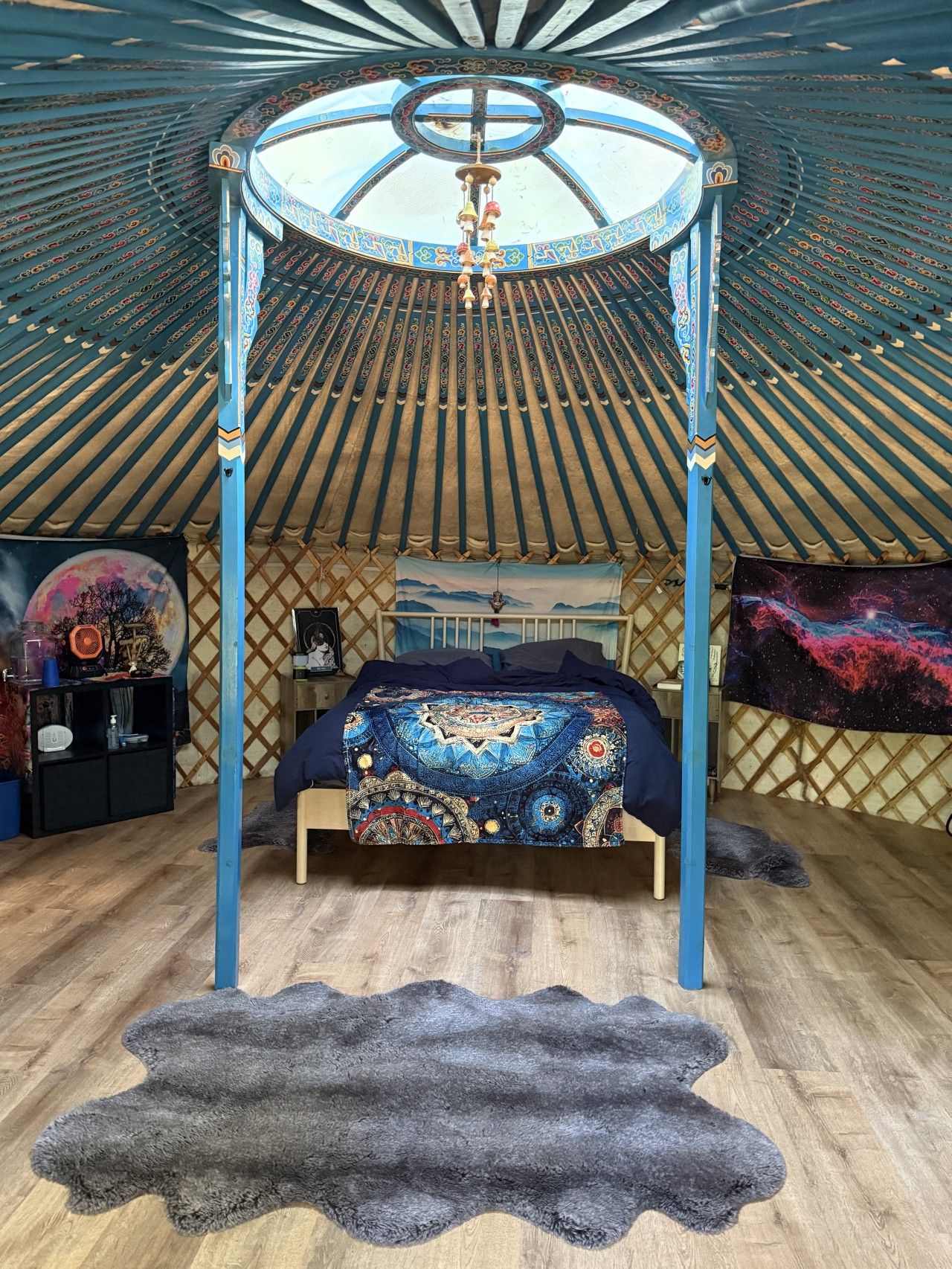 A room with a four-poster bed, a hanging light fixture, and a large tapestry on the wall.