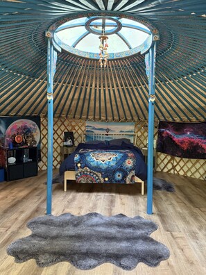 A room with a four-poster bed, a hanging light fixture, and a large tapestry on the wall. - Soul Yurt-Glamping | Cedar Hot Tub | 1 hr to Mt Rainier (Buckley)