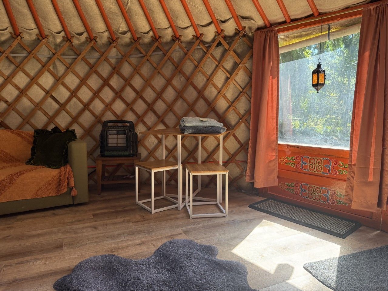 A cozy room with a bed, a TV, and a window with curtains.