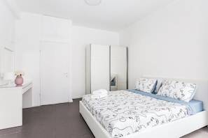 A modern bedroom with a bed, a dresser, a mirror, and a door.