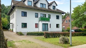 Une maison à deux étages avec une allée pavée, un jardin verdoyant et un mur de briques en arrière-plan.