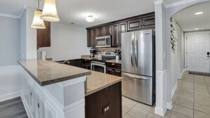 Una cocina moderna con encimeras de granito, electrodomésticos de acero inoxidable e iluminación colgante.
