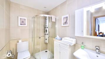 A modern bathroom with a glass-enclosed shower, a toilet, a sink, and a cabinet.
