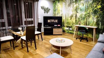 En moderne stue med et stort fladskærms-tv, et rundt sofabord og en sofa.