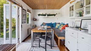 Un coin repas chaleureux avec une table en bois, des chaises et un banc agrémenté de coussins colorés.