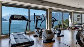 A spacious gym with a treadmill, elliptical, and stationary bike, large windows with a mountain view. - Luxury Apartment Lake view in Montreux by GuestLee (Montreux)