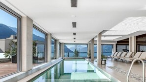 A modern indoor swimming pool with large windows offering mountain views. - Luxury Apartment Lake view in Montreux by GuestLee (Montreux)