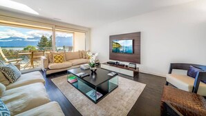 A modern living room with a sofa, coffee table, and TV. - Luxury Apartment Lake view in Montreux by GuestLee (Montreux)