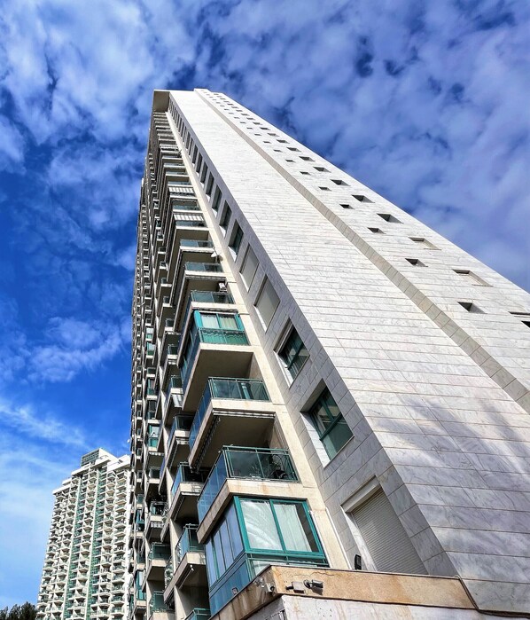 A high-rise building with multiple balconies and a clear sky.