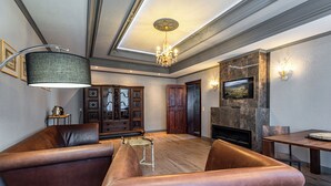 A spacious living room with leather sofas, a chandelier, a fireplace, and a television mounted on the wall. - Villa Hänsch (Grossschoenau)