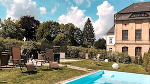 A swimming pool with lounge chairs and a building in the background. - Villa Hänsch (Grossschoenau)