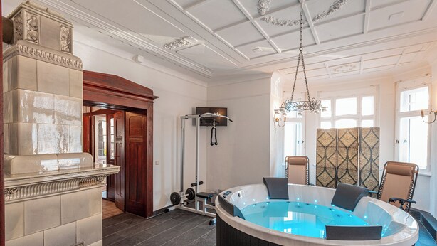 A spa room with a hot tub, exercise equipment, and a wooden reception desk. - Villa Hänsch (Grossschoenau)