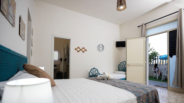 A bedroom with a bed, a bedside lamp, a clock, and a view of the outside. - SALUTAMU (Misiliscemi)