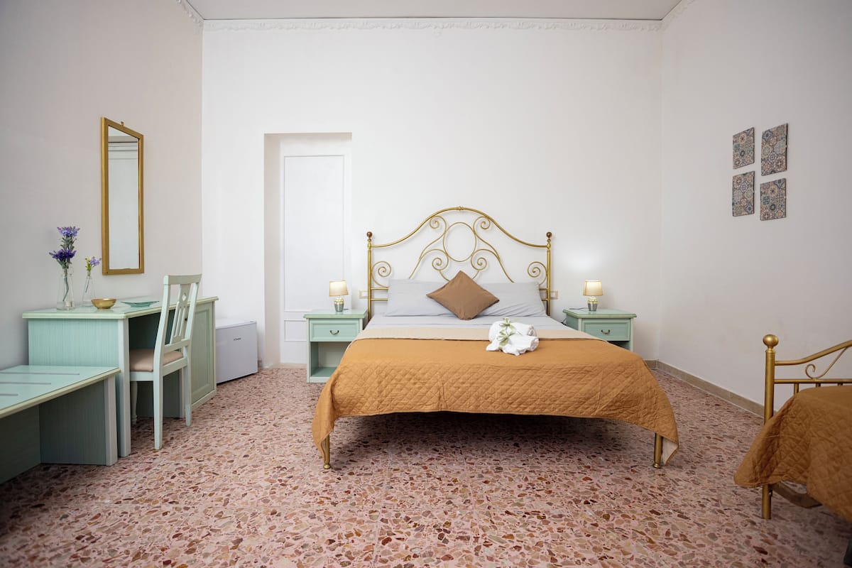 Un dormitorio con cama, mesitas de noche, escritorio y una silla.