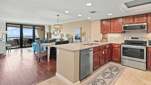 A spacious kitchen with a large island, stainless steel appliances, and wooden cabinets. - Updated beach condo with stunning views! (Miramar Beach)