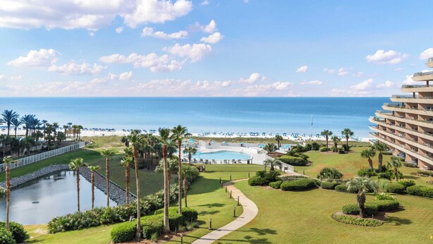 A resort with a pool, palm trees, and a view of the ocean. - Updated beach condo with stunning views! (Miramar Beach)