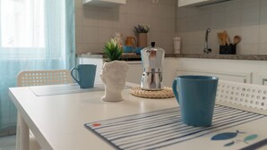 Eine Küche mit weißem Arbeitsplatz, einer Kaffeemaschine, einer blauen Tasse und einer Zierpflanze.