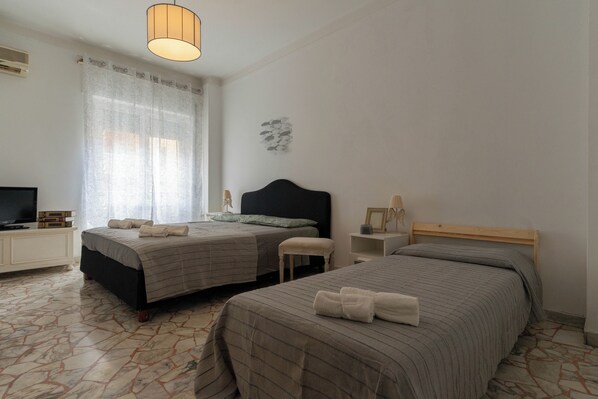 A hotel room with two beds, a television, a small table, and a decorative wall piece.