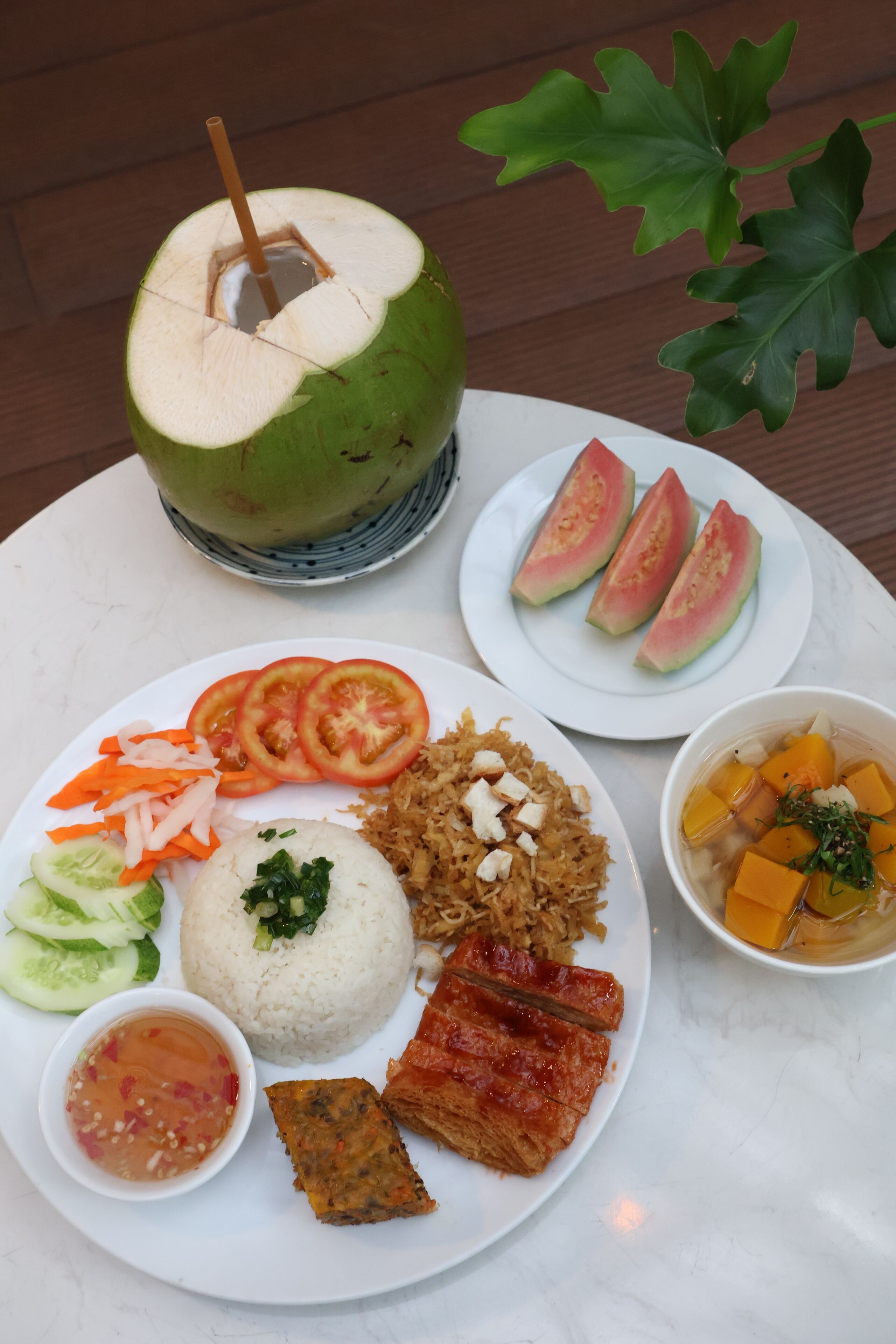 Une table garnie d’une variété de plats, notamment du riz, des légumes et de la viande, ainsi qu’une boisson à base de noix de coco.