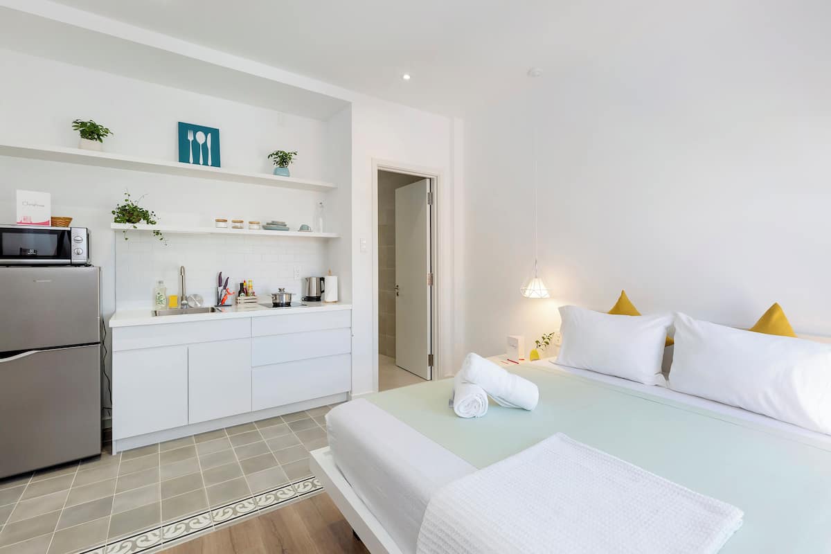 A hotel room with a bed, a kitchenette, a microwave, and a door leading to a bathroom.