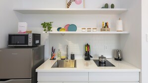 Uma cozinha moderna com geladeira de aço inoxidável, micro-ondas, pia e diversos utensílios de cozinha.