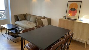 Ett modernt vardagsrum med en soffa, ett matbord med stolar och ett litet sidobord.