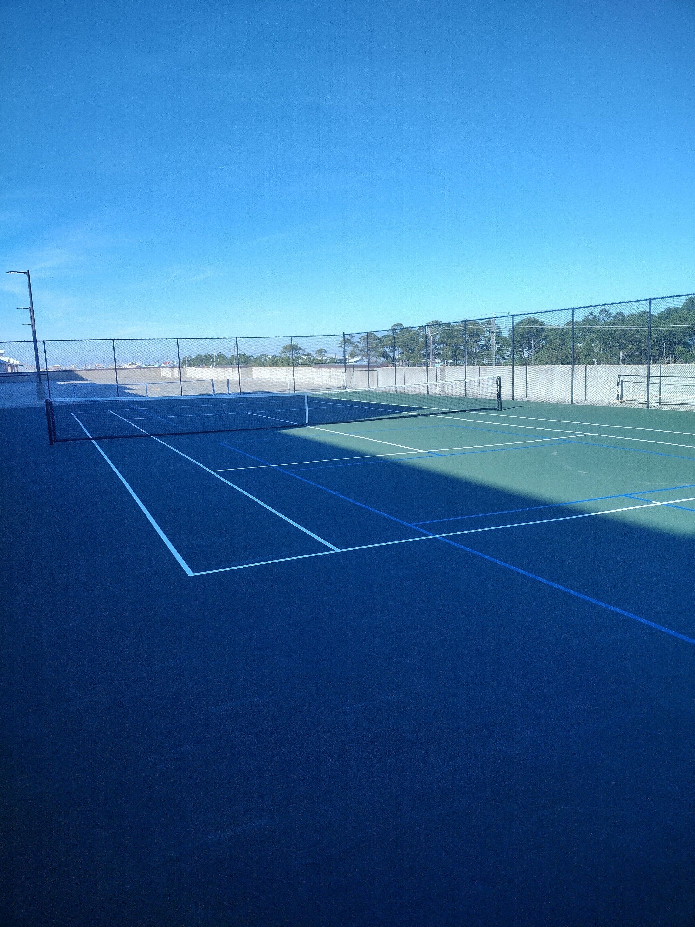 Een buitenbaan voor tennis met een heldere lucht.