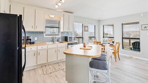 Una cocina moderna con armarios blancos, un refrigerador negro y una isla de madera.