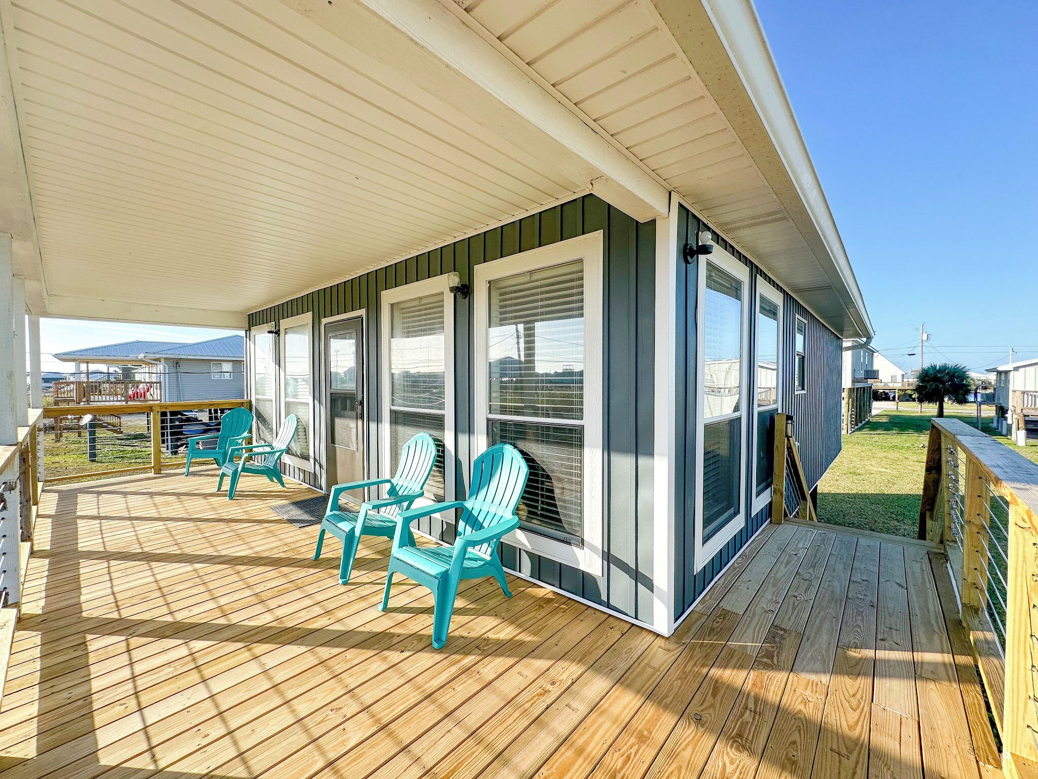 Une terrasse couverte avec un plancher en bois et des chaises turquoise.