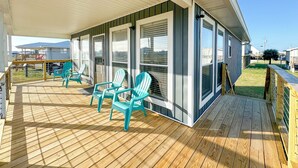 Una terraza techada con piso de madera y sillas turquesas.