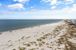 A beach with a clear sky, sandy shore, and beach umbrellas. - March/April Discount - Beautiful home steps away from Gulf of Mexico Beaches  (Dauphin Island)