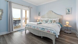 Een slaapkamer met een groot bed, een plafondventilator en uitzicht op de omgeving via een schuifdeur.
