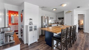 Een moderne keuken met witte kastjes, roestvrijstalen apparatuur en een houten kookeiland.