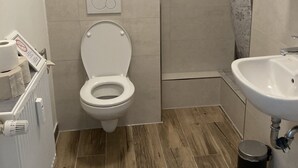 Un baño con inodoro, ducha y lavamanos.