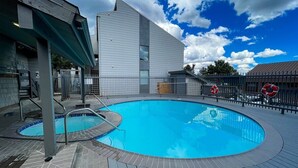 A swimming pool with a wooden deck, a lifeguard tower, and a building in the background. - Krystal Villa East 303- Nice, Central to Town (Mammoth Lakes)