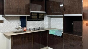 A kitchen with dark wooden cabinets, a stainless steel sink, and a gas stove.