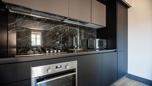 A modern kitchen with dark cabinetry, a built-in oven, and a microwave. - Residence  Thym N3003 (Lucca)