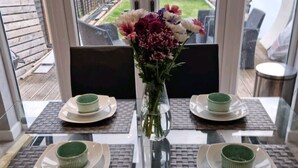 A dining table set for four with a vase of flowers in the center. - Remarkable 3-bed House in Chelmsford (Chelmsford)